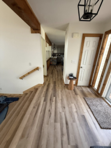 A renovated entryway with new flooring, baseboards, and a wooden handrail by M Squared Construction LLC in Tonganoxie, KS.