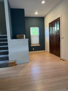 A modern entryway featuring newly installed hardwood flooring and a dark accent wall by Nelson Hardwood Flooring in Madison, WI.