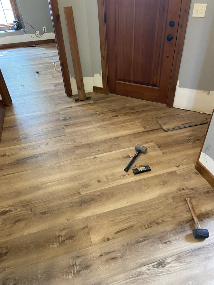 Entryway and hallway with new laminate flooring and tools, showcasing work by RT Handyman LLC in Sioux Falls, SD.