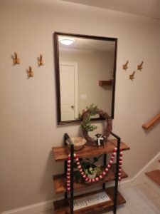 An entryway featuring a large mirror and multiple coat hooks professionally installed by Dovetails Services LLC in Derry, NH.
