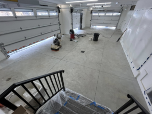 A wide view of a garage floor being prepared with grinding equipment by DuraFloor Epoxy Pros in Akron, OH.