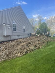 Large pile of excavated dirt next to a house foundation, indicating ongoing basement work by Pioneer Basement Solutions in Canton, OH.