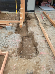 Excavated trenches and wooden forms prepared for concrete pouring by Smith Finishes LLC in Everett, WA.