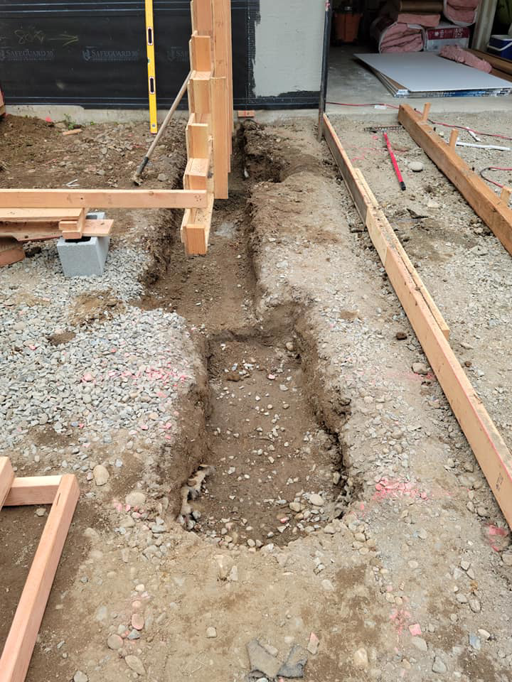 Excavated trenches and wooden forms prepared for concrete pouring by Smith Finishes LLC in Everett, WA.