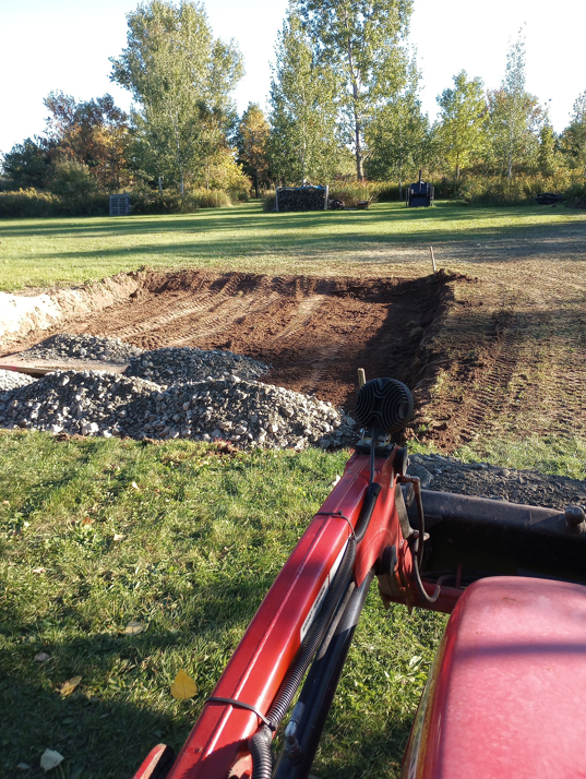 An excavated trench and gravel pile viewed from a tractor bucket by Todd's Mini-Tractor/Backhoe Services in Appleton, WI.