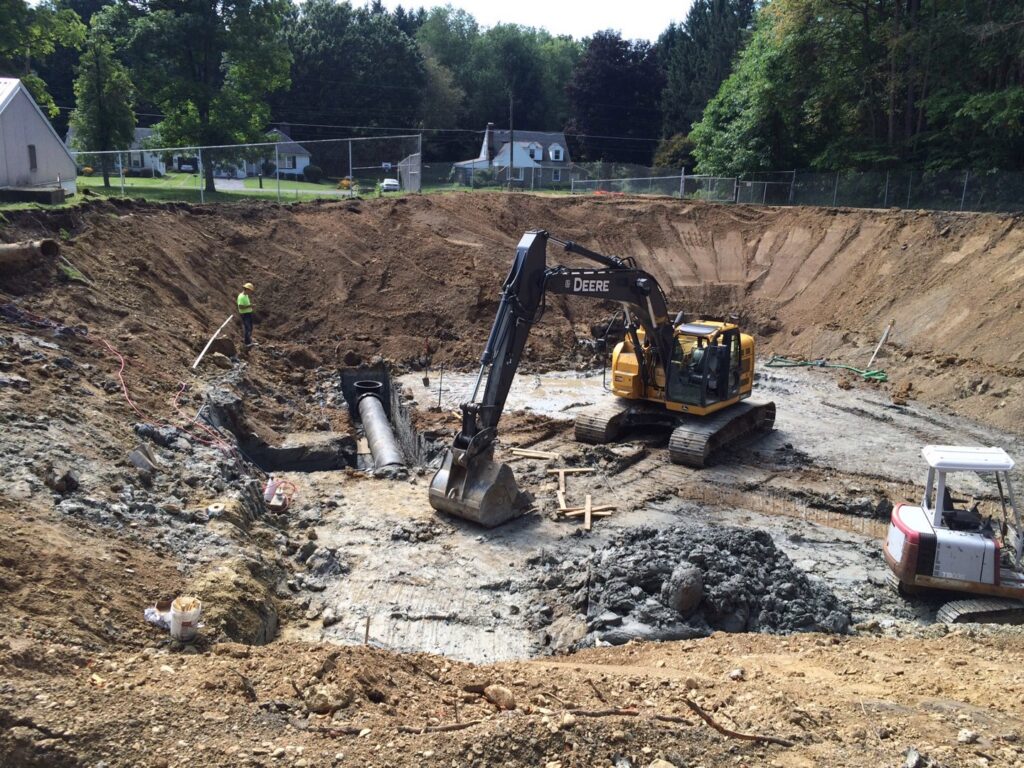 An excavation site with utility pipe installation and heavy equipment by Wilkinson Excavating, Inc. in Meadville, PA