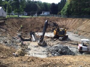 An excavation site with utility pipe installation and heavy equipment by Wilkinson Excavating, Inc. in Meadville, PA
