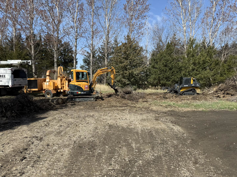 An excavator, wood chipper, and skid steer working on tree removal debris for Dakota Tree Company in Aberdeen, SD