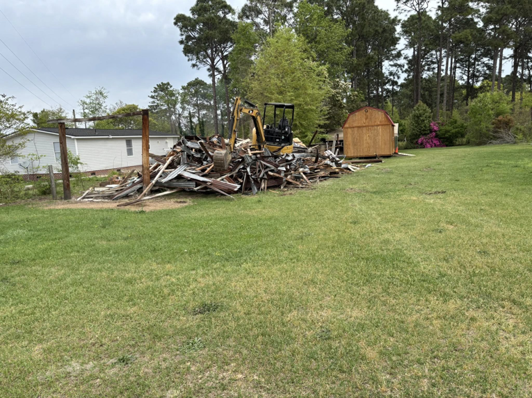 An excavator clearing a large pile of demolition debris for BRR services in Fayetteville, NC
