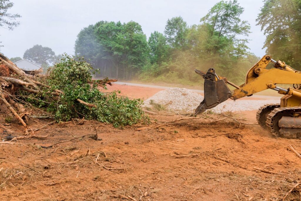 An excavator clearing tree branches and organic debris from a property by West Way Landwork in New Market, AL.