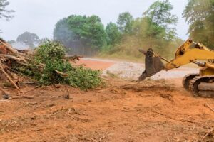An excavator clearing tree branches and organic debris from a property by West Way Landwork in New Market, AL.