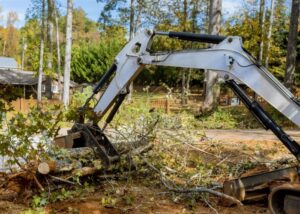 An excavator clearing tree debris and branches after a tree service job by Rhode Island Tree Removal in Providence, RI.