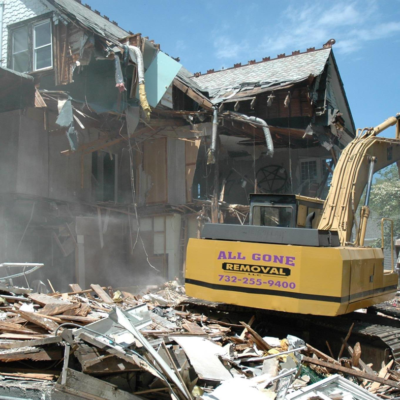 An excavator from All Gone Removal Demolition & Junk Dumpster Containers demolishing a house in Toms River, NJ.