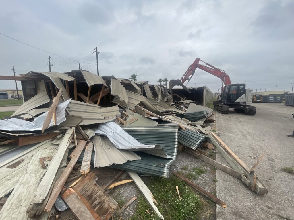 An excavator from White Star Services LLC demolishing a structure and creating a large pile of debris in Corpus Christi, TX.