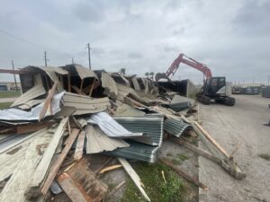 An excavator from White Star Services LLC demolishing a structure and creating a large pile of debris in Corpus Christi, TX.