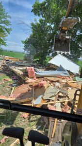 View from an excavator showing a large pile of demolition debris, indicating a cleanup job by Rubble Removers LLC in Riverton, WY.