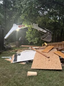An excavator loading construction debris into a large dumpster during a junk removal job by Dumpin' Junk in Martinsburg, WV.