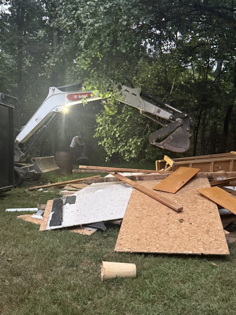 An excavator loading construction debris into a large dumpster during a junk removal job by Dumpin' Junk in Martinsburg, WV.