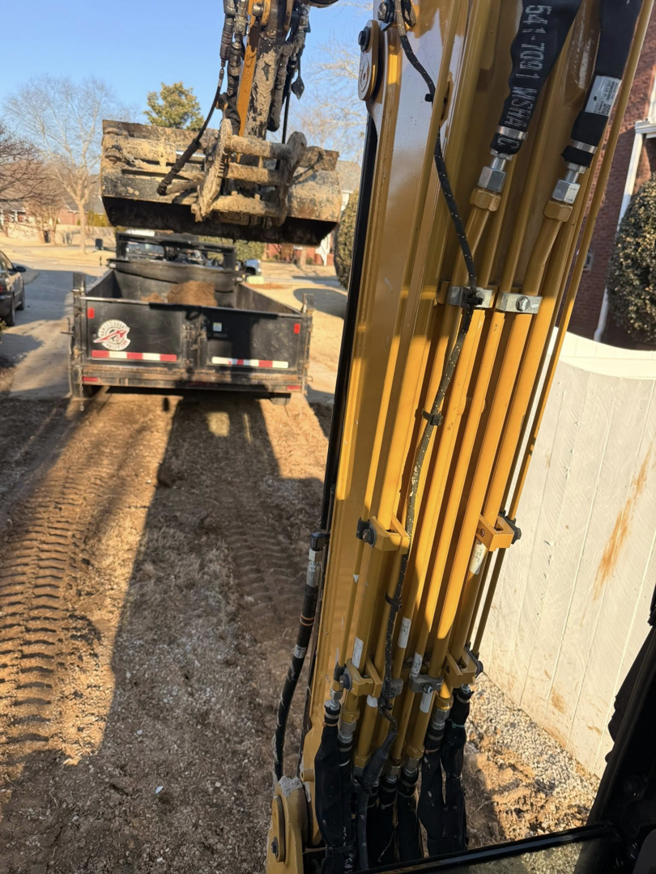An excavator loading construction debris into a dump trailer for removal by West Way Landwork in New Market, AL.