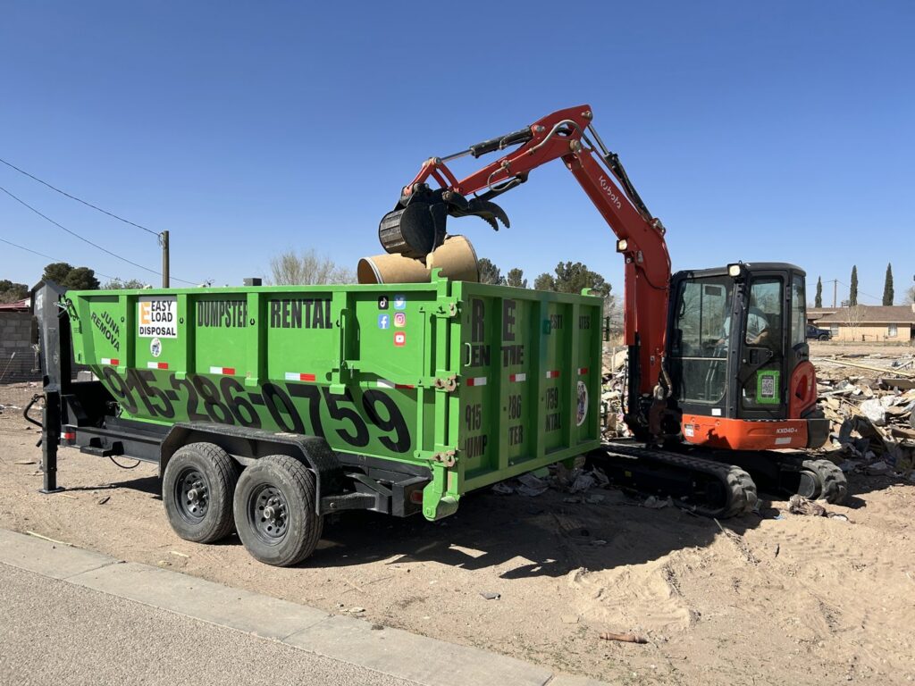 An excavator loading construction debris into a green dumpster trailer for Easy Load Disposal El Paso in El Paso, TX.
