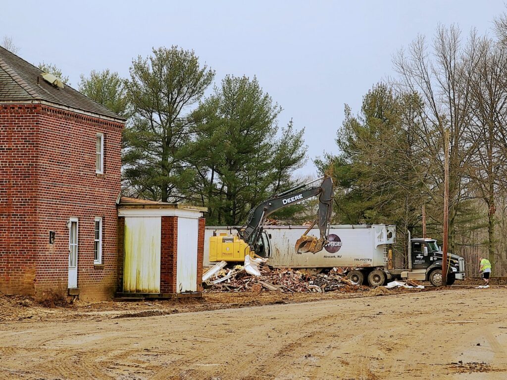 An excavator loading construction debris into a Voyager Trucking trailer during a junk removal job in Newark, NJ