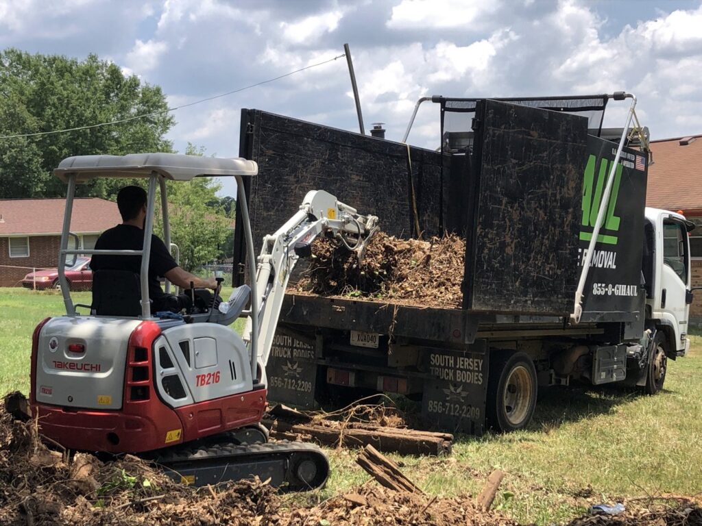 An excavator loading debris into a G.I.HAUL ATLANTA junk removal truck during a job in Atlanta, GA.