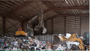 An excavator with a grapple attachment moving a large pile of junk for Bulk Environmental and Industrial in Miami, FL