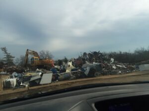 An excavator moving a large pile of scrap metal and junk at the CycleMET inc. facility in Columbus, OH.