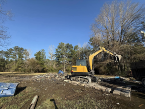 An excavator actively removing a large pile of debris and junk for Junk Removal Veterans LLC in Deridder, LA.
