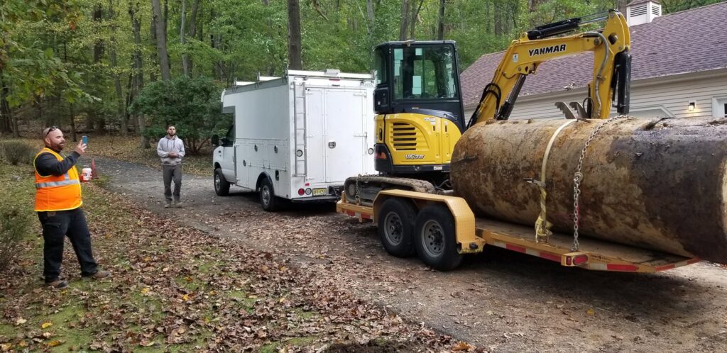 An excavator removing a large tank, demonstrating a junk removal job by All American Alloys and Recycling Inc. in Elizabeth, NJ.