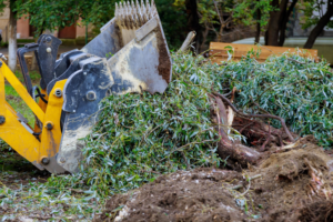 An excavator removing a tree stump and debris, part of services by Carolina Property Solution and Tree Service in Concord, NC.