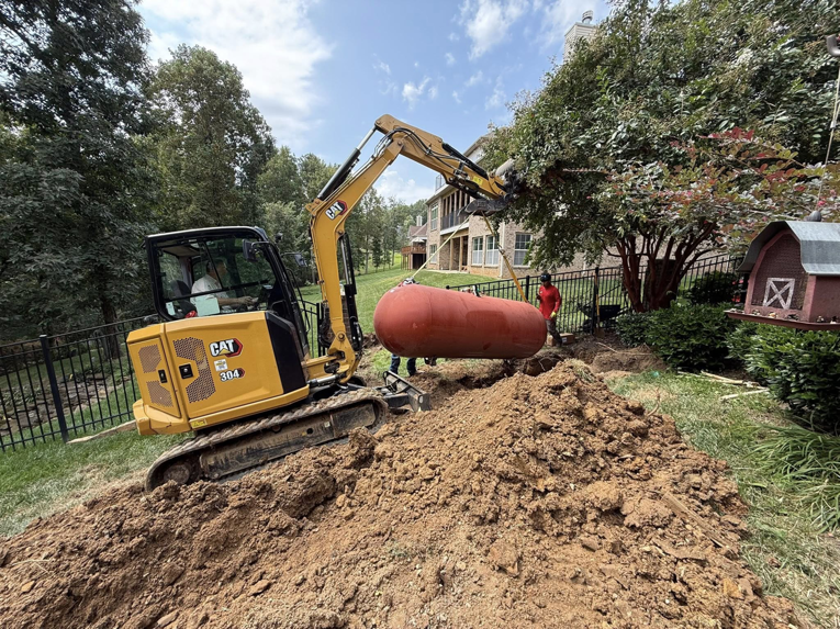 An excavator carefully removing a large underground tank from a property by West Way Landwork in New Market, AL.