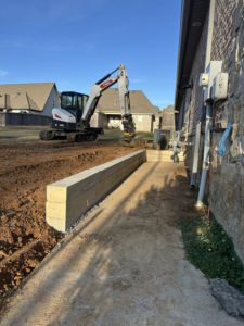 An excavator working on a retaining wall construction project by Louisiana Land Solutions in West Monroe, LA.