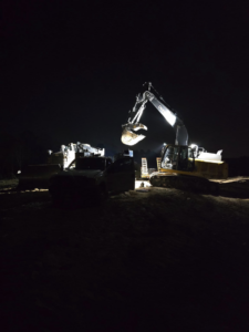 An excavator and a service truck working at night, demonstrating emergency equipment service by Wise Equipment Services in Rock Hill, SC.