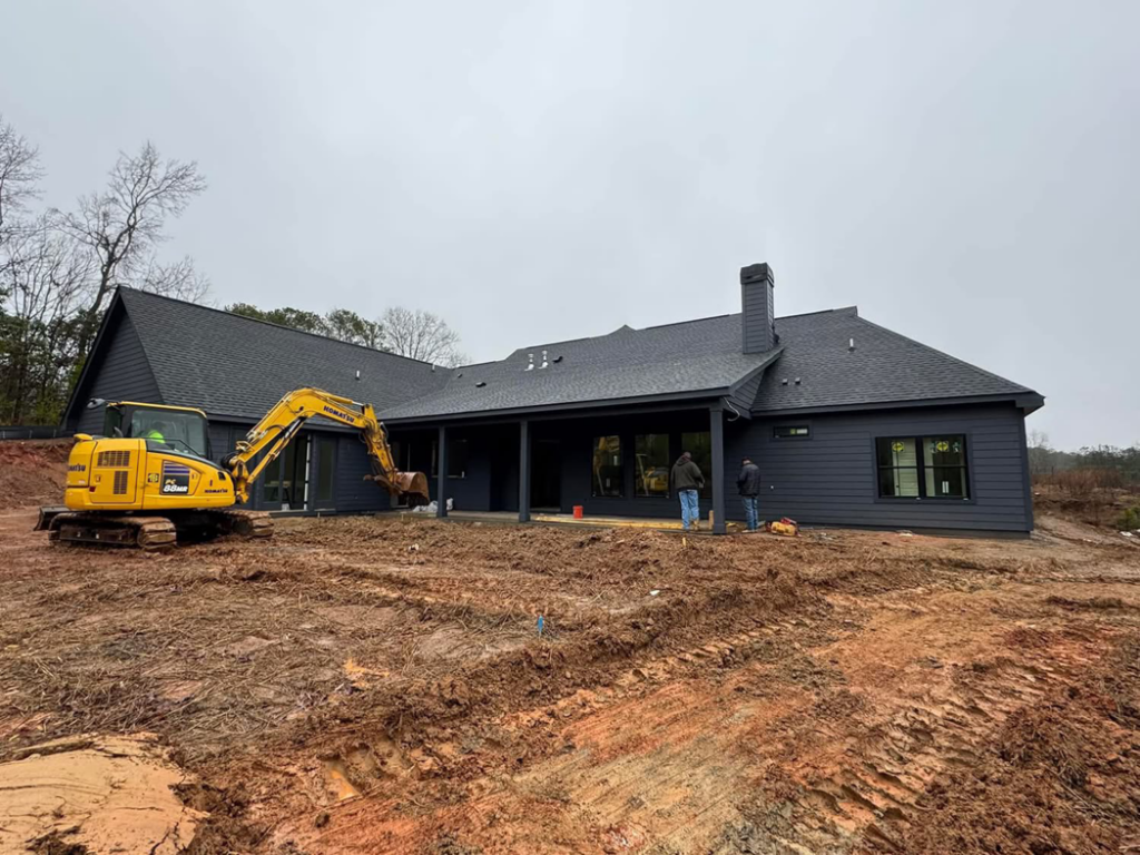 An excavator and workers performing site preparation for a new pool or outdoor living area by Creative PoolScape in Canton, GA.