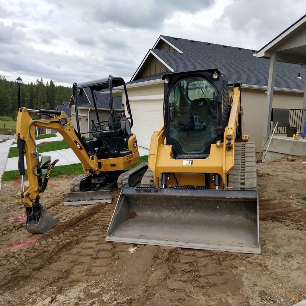 A mini excavator and a skid steer loader parked at a residential construction site by Aspen Excavation in Spokane, WA.
