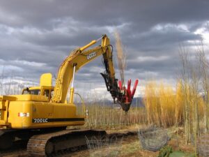 An excavator with a tree spade attachment performing tree transplanting for Trees Inc - Wyoming in Jackson, WY