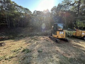 An excavator and wood chipper on a site, showing land clearing services by JTE & Company in Oxford, MA.