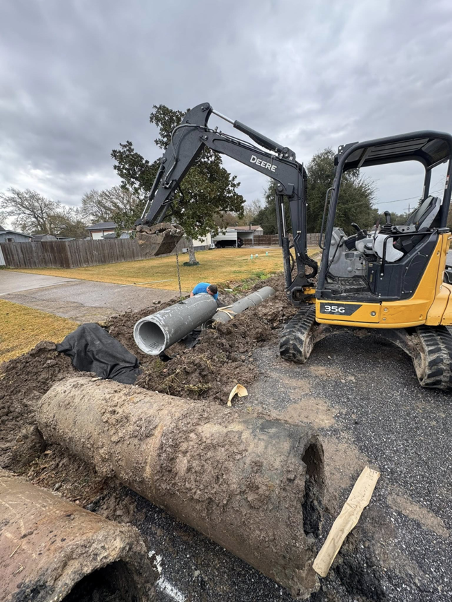 An excavator and worker installing drainage pipes for a project by Rolloff Rentals / Rolloff Services in Port Angeles, WA.