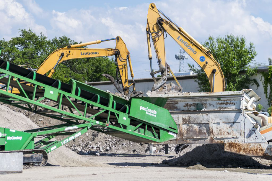 Excavators loading construction debris onto a conveyor belt system at Global Recycling of Tampa Bay in Tampa, FL.