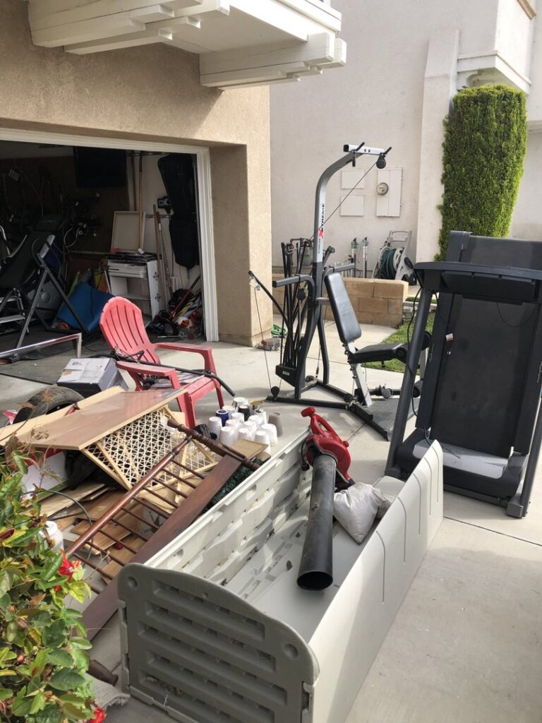 Old exercise equipment and outdoor storage bins on a driveway for removal by The Junk Gentlemen in Anaheim, CA.