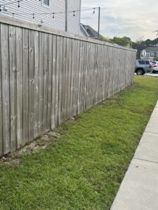 An existing weathered wooden privacy fence running alongside a sidewalk, maintained by Frontline Fencing LLC in Summerville, SC.