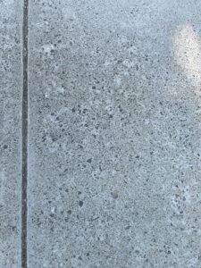A close-up of an exposed aggregate concrete surface with a control joint, installed by concrete poured & installed - cp&i in Buffalo, NY.
