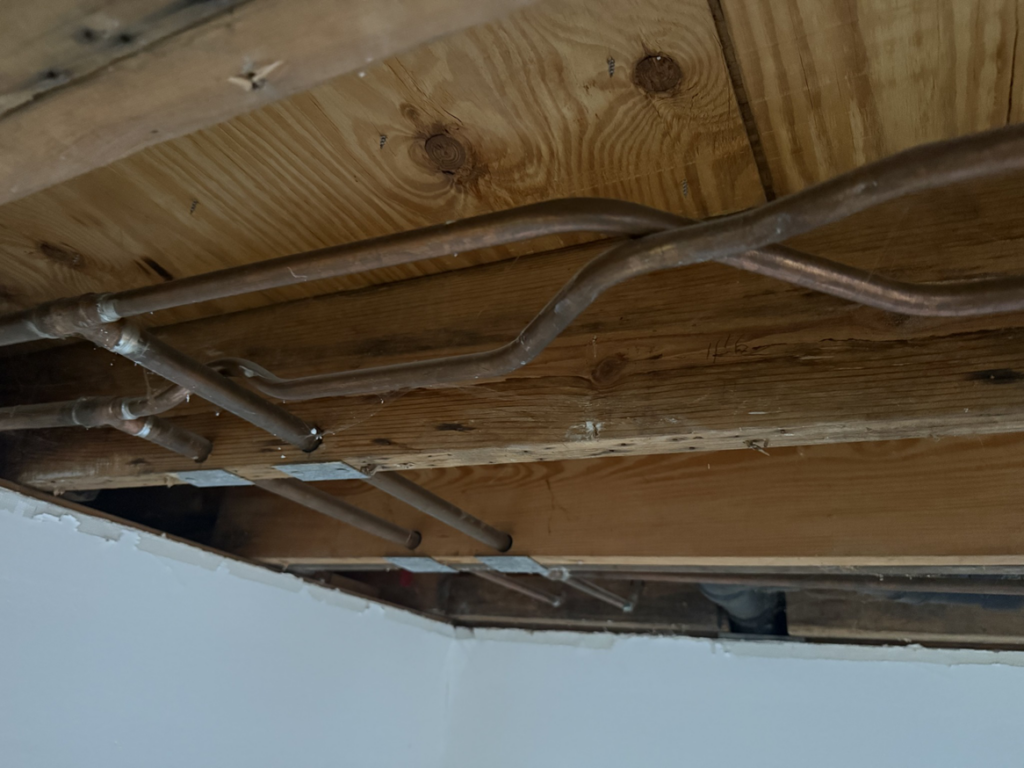 Exposed copper plumbing pipes installed under a floor or ceiling, showcasing plumbing work by JRG General Home Services, LLC in Toms River, NJ.