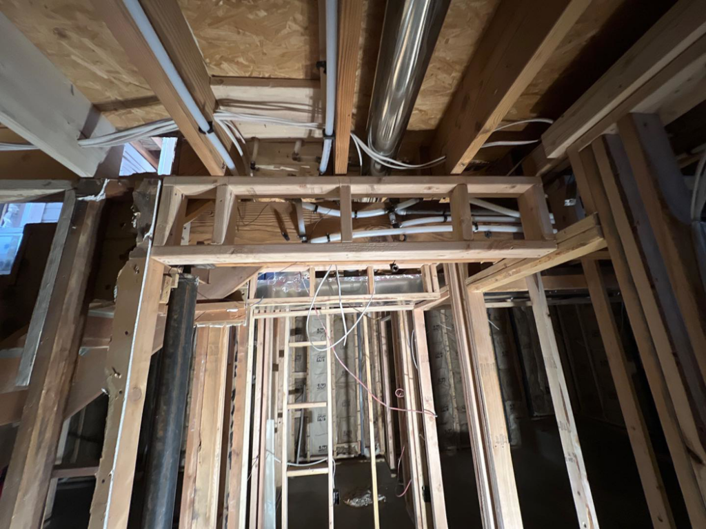 Exposed plumbing pipes and electrical wiring within a framed ceiling and wall structure by Kliesen Construction Company in Pueblo, CO.