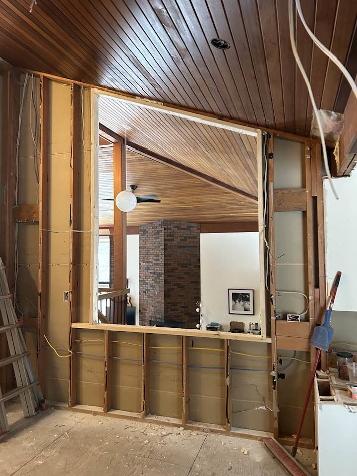An exposed interior wall with wooden framing and electrical wiring during a renovation by Haus Builders in Goodhue, MN