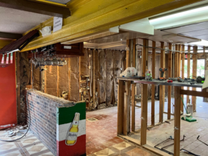 An extensive interior renovation showing exposed studs and a demolished bar area by JB Renovations in Houston, TX.