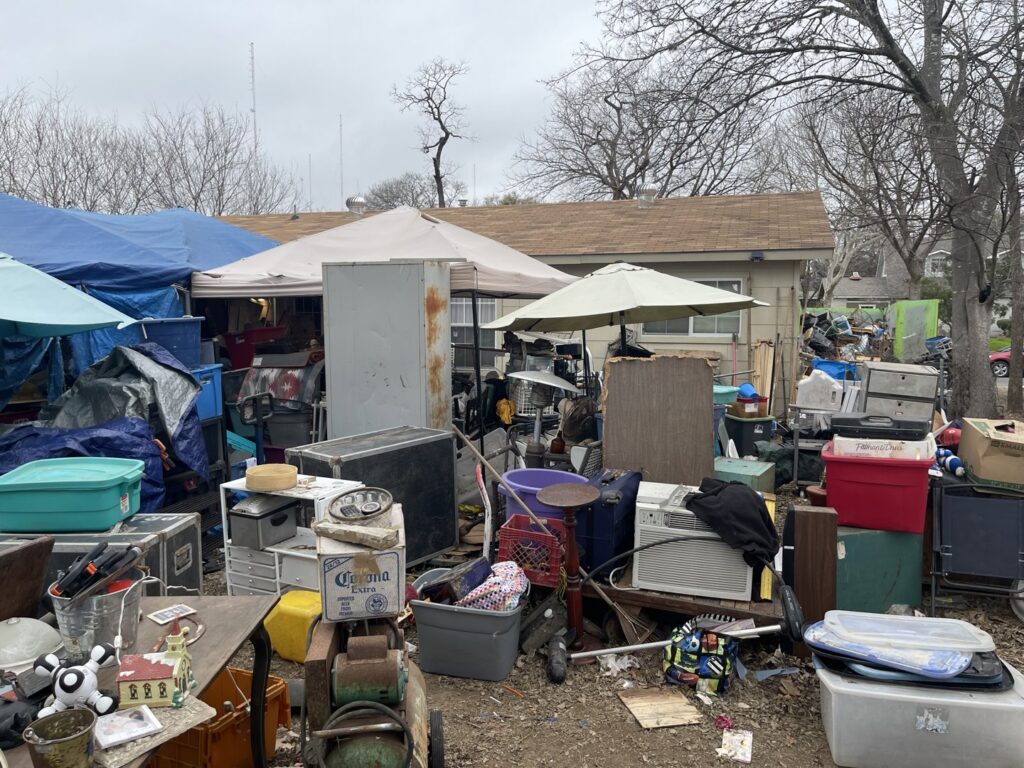 An extensive outdoor area filled with clutter, tarps, and various items, indicating a large junk removal project by JunkStart in San Antonio, TX.