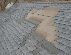 Extensive asphalt shingle roof damage with exposed plywood decking, ready for repair by Castle Contracting Group in Cincinnati, OH.