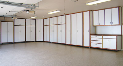 An extensive white garage cabinet system with brown trim, tall storage, and base cabinets installed by NW Garage Cabinet Company in Ridgefield, WA.